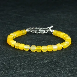 Gedetailleerd weergave van gele gefaseerde natuurstenen kralen armband met zilveren sluiting.