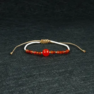 Handmade woven beaded bracelet with red center bead and adjustable cord for women.