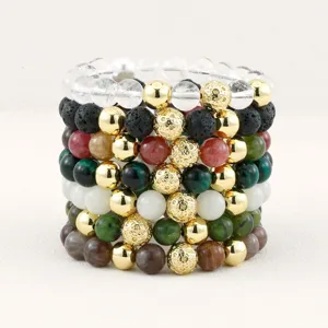 Detail view of layered gemstone beaded bracelets featuring crystals, lava stones, and gold beads.