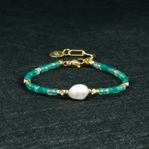 Detailopname van de groen kralen armband met onregelmatige parel en gouden accentdetails.