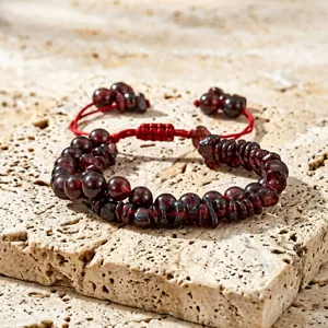 Gedetailleerde close-up van granaat kralenarmband met rood geweven verstelbaar koord.