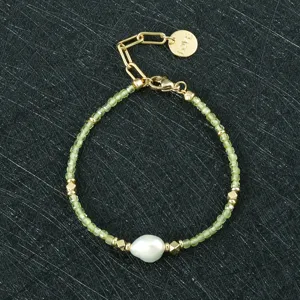 Detail van de onregelmatige parel- en groene kraal armband met metalen bedels en ketting.