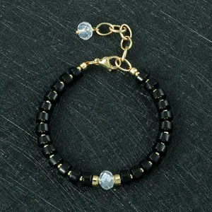 Elegant armband detail met zwarte kralen gouden accenten en heldere kristallen hanger.