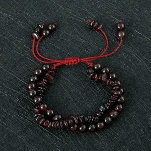 Gedetailleerd overzicht van handgemaakte granaat kralen armband met rood trekkoord.