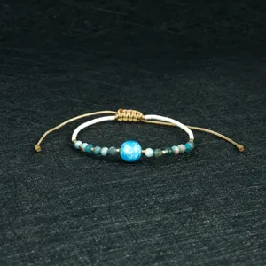 Handmade woven beaded bracelet with blue central bead, vintage adjustable string jewelry.