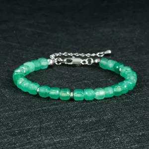 Close-up van de groene gefacetteerde natuurstenen armband met zilveren metalen afstandshouders.