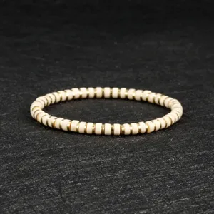 Detailed view of the bohemian style heishi bead bracelet with golden spacers on dark surface.