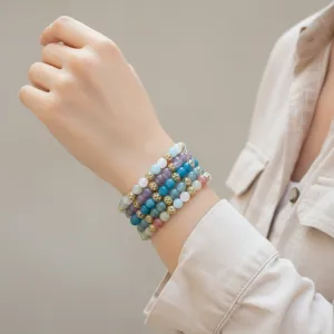 Gedetailleerd overzicht van de gelaagde gekleurde halfedelsteen kraal armband set op pols.
