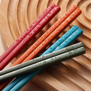 Detailed view of colorful alloy chopsticks with water droplets on a wooden textured background.