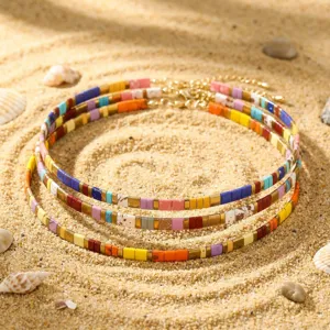 Nahaufnahme der farbigen bohemischen Perlen-Halskette mit TILA-Quadraten am Strand.