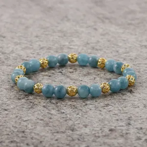 Detailopname van blauwe steen kralen armband met gouden holle metalen kralen op grijze achtergrond