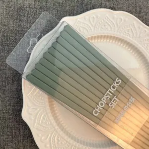 Set di bacchette in lega verde in scatola trasparente, ideale per casa moderna e hotel.