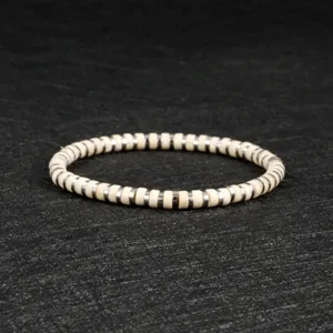 Detailed closeup of a beaded bracelet featuring white disc beads and metallic spacers.