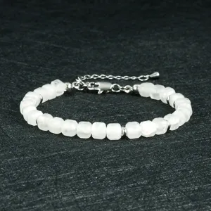 Close-up van een wit gefacetteerd edelsteen kralenarmband met metalen tussenstukken en ketting.