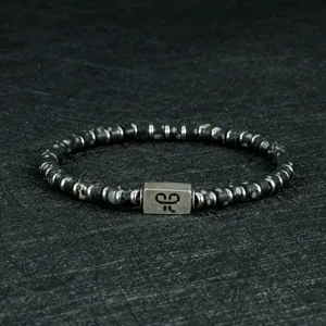 Gedetailleerd overzicht van heren kralenarmband met stenen kralen en metalen bedel.