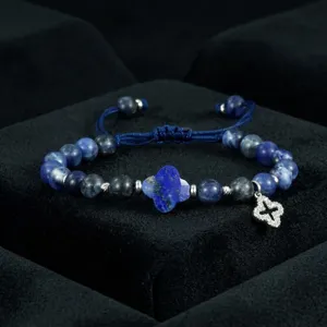 Detailopname blauwe lapis lazuli kralen armband met klaverblad hanger verstELbaar sieraad.