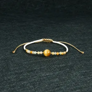 Handmade beaded bracelet detail shot showing yellow gemstone and woven string design.