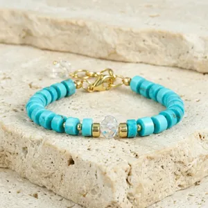 Close-up van de blauwe steen kralen armband met kristallen bedel en goudkleurige details.