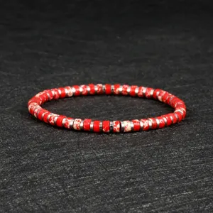 Close-up detail of a red stone and metal spacer beaded stretch bracelet, bohemian style.
