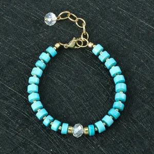 Gedetailleerde close-up van de 6mm turquoise kralenarmband met blauwe cilinders en gouden accenten.