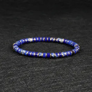 Close-up detail of blue stone disc beaded bracelet with metallic spacer beads on dark slate surface.