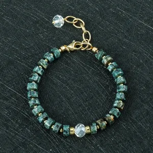 Close-up van toermalijn edelsteen kralenarmband met 6mm schijfkralen en gouden afstandhouders.