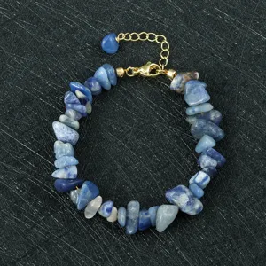 Gedetailleerd overzicht van onregelmatige blauwe steenslag armband met gouden verstelbare sluiting.