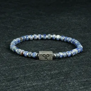 Detailopname van een blauwe sodaliet edelsteen kralenarmband met gegraveerde metalen spacer.