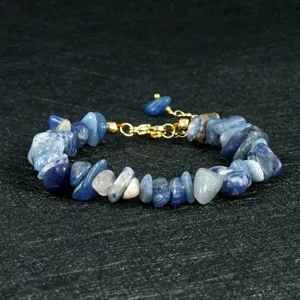 Close-up detail van onregelmatige blauwe en roze chipstenen armband met gouden ketting.