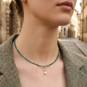 Dettaglio della collana di perle verdi vintage con anello dorato e pendente di perla.