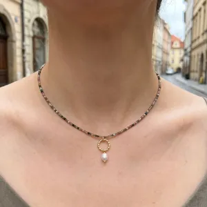 Dettaglio in primo piano della collana di perle vintage con ciondolo e anello d'oro.