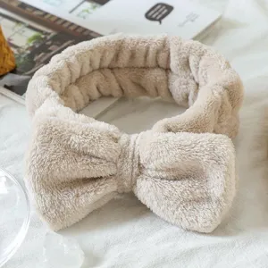 Detail shot of a soft fluffy bow headband in beige, perfect for skincare and makeup routines.