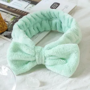 Mint green fuzzy bow spa headband for face washing, makeup, and skincare routines daily.