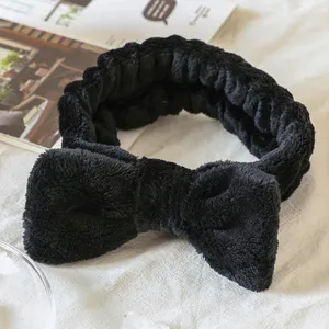 Close-up of black plush bow headband, soft texture design for daily makeup and skincare.