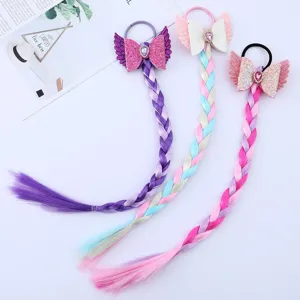 Primo piano di trecce parrucca colorate per bambini con fiocchi glitter e elastici per capelli.