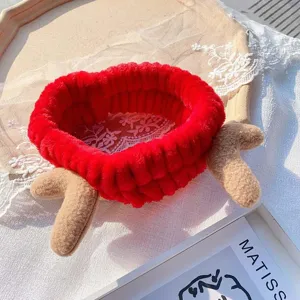 Detailed shot of a cute red coral fleece reindeer antler headband, soft plush hair hoop for washing.