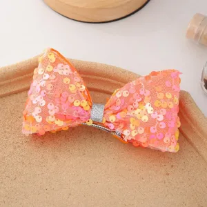 Gros plan détaillé d'une jolie pince à cheveux nœud à sequins orange avec paillettes.
