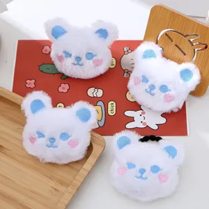 Dettaglio dell'elastico per capelli a forma di orsetto di peluche bianco con orecchie blu.