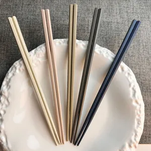 Primo piano dettagliato di bacchette giapponesi multicolore in lega su piatto bianco, cucina.
