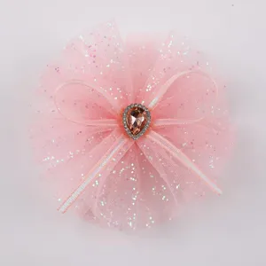 Dettaglio molletta per capelli con fiocco in tulle glitterato rosa, accessorio per bambini.