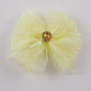 Dettaglio del fiocco per capelli in rete gialla, con glitter lucidi e strass centrale.