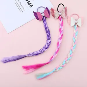 Close-up detail view of colorful braided hair extensions with sparkly bows and cute wings.
