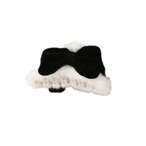 Black and white plush bow hair claw clip detail, fluffy faux fur and velvet texture close-up
