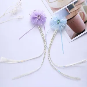 Close-up of children's mesh bow hair clips with long braided hair extensions in purple and blue.