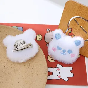 Vista dettagliata della molletta per capelli e spilla in peluche di orsetto bianco, accessorio.
