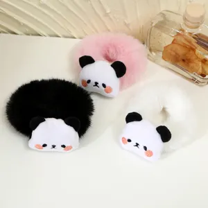 Close-up detail of cute cartoon panda plush hair scrunchies in three colors on white table.