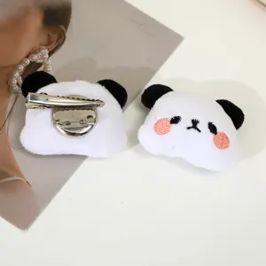 Close-up detail of cute plush panda hair clip with metal brooch pin, soft fluffy texture.