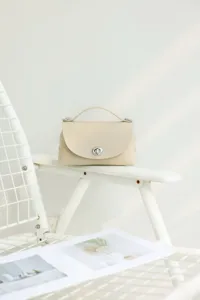 Elegante bolso cruzado de piel de vaca beige con cierre metálico elegante y asa.
