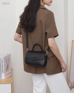 Detail view of black genuine leather flap handbag, vintage style with top handle and strap.