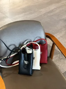 Mini sac bandouliere vertical en cuir PU noir blanc rouge avec detail de fermoir metallique.